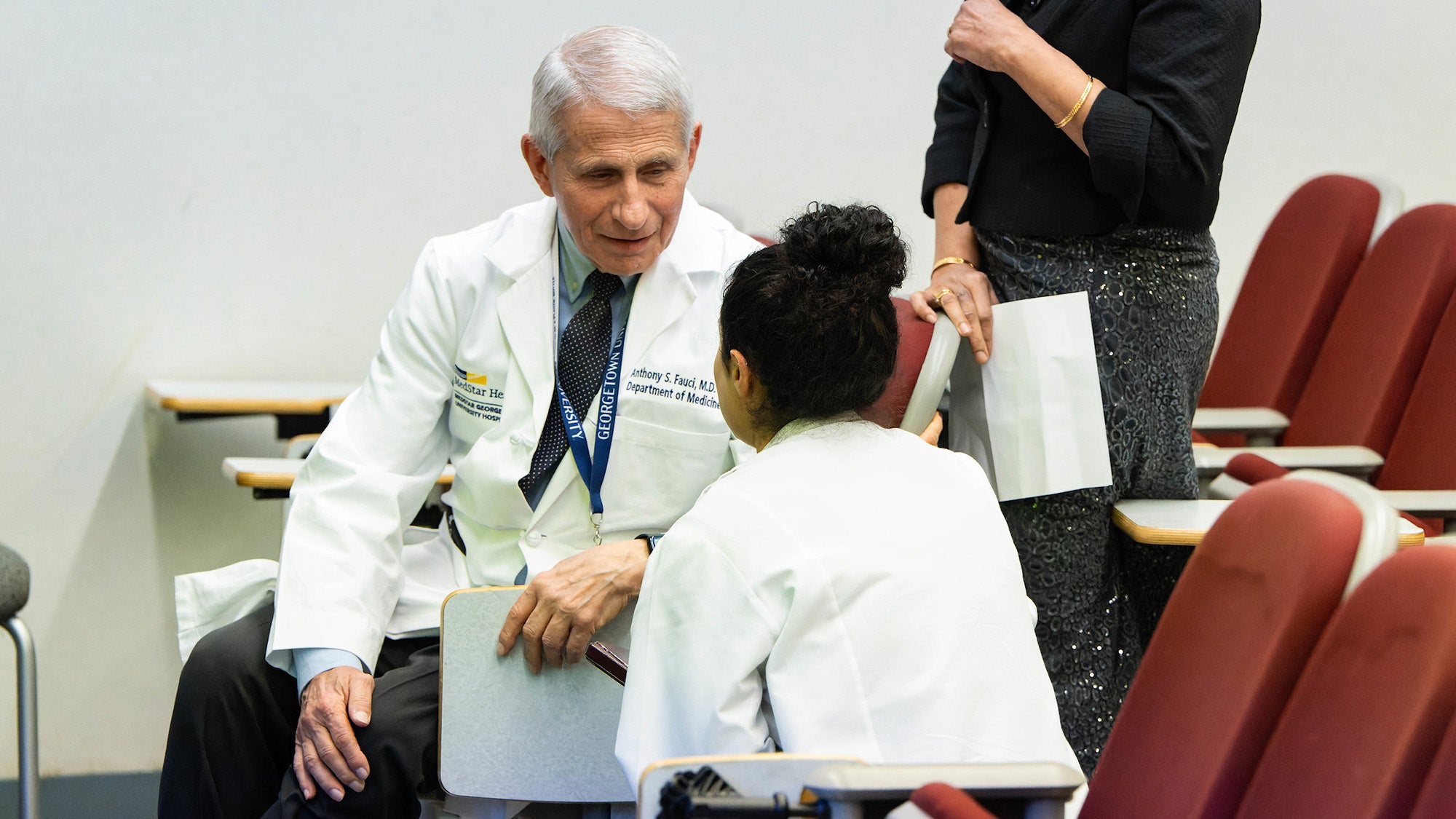 Dr. Fauci speaks with a student in an auditorium