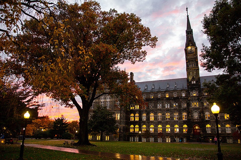Healy Hall and trees silhouetted against a sunset