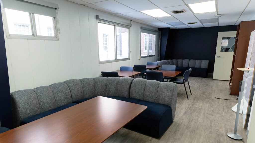 A room with windows is filled with couches, tables and chairs