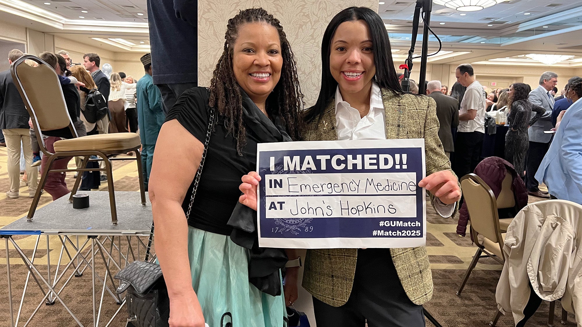 A woman hold her Match Day sign as she and her mother stand side by side