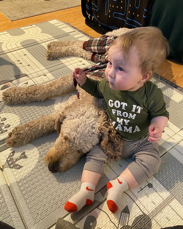 A baby and dog sit on the floor