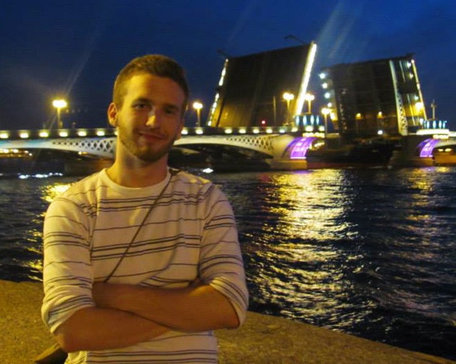 A night view where Joe Scott sits in the foreground with an open drawbridge over the Neva River in the background