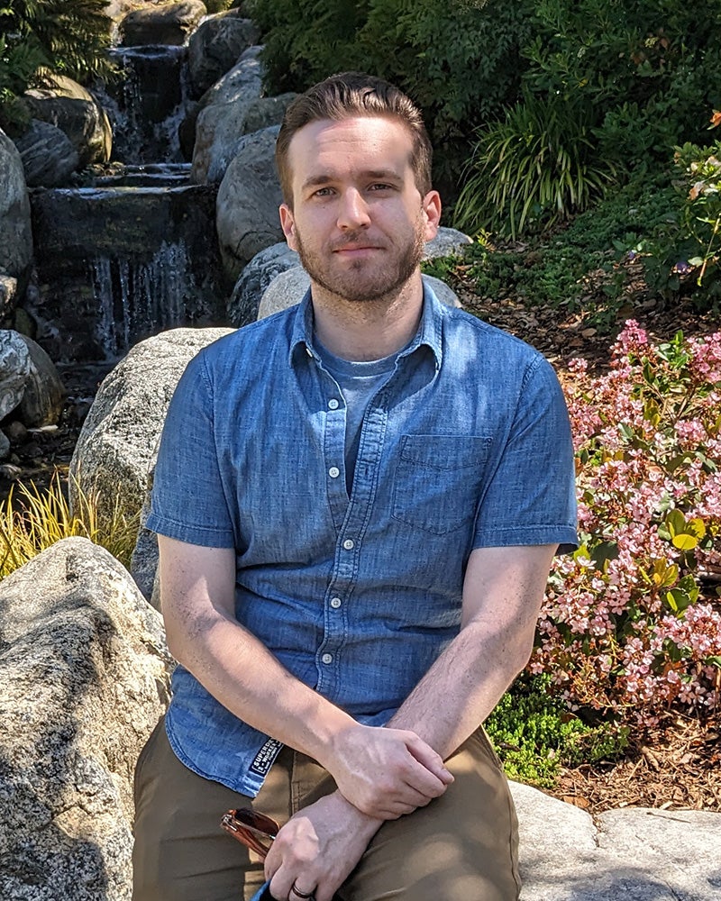 Joe Scott sits in a garden with a waterfall in the background