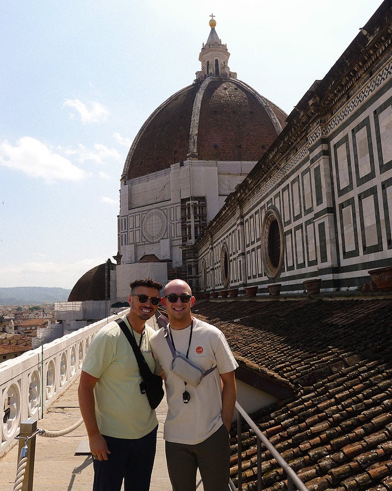 Two people stand together with the Duomo in the background