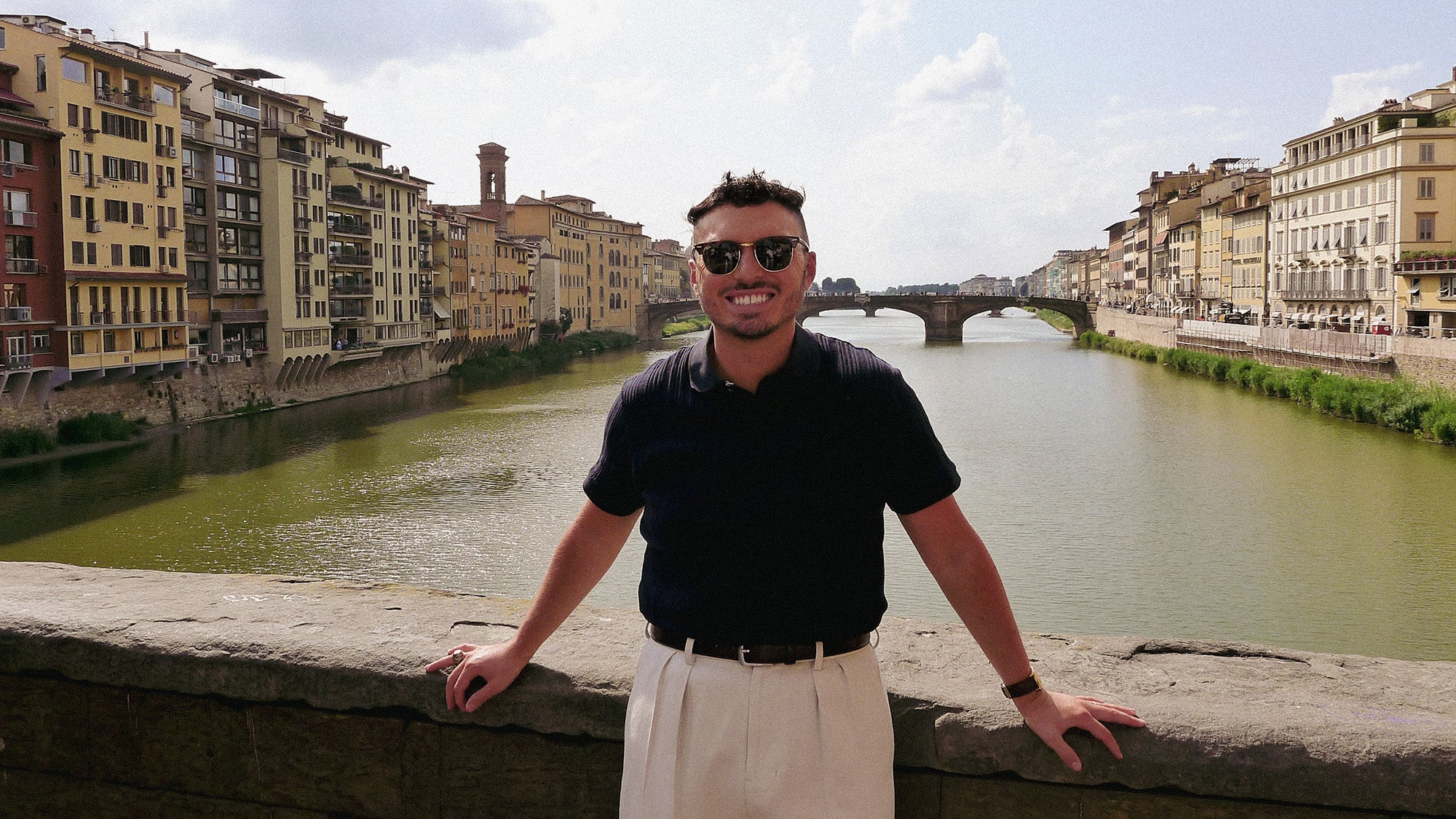 Bryson Daniels-Stevens stands on a bridge in Florence with a river beneath and behind him
