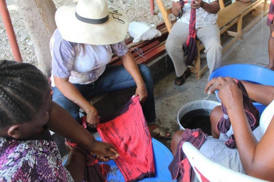 Several youth work on tie dyeing fabric in Haiti