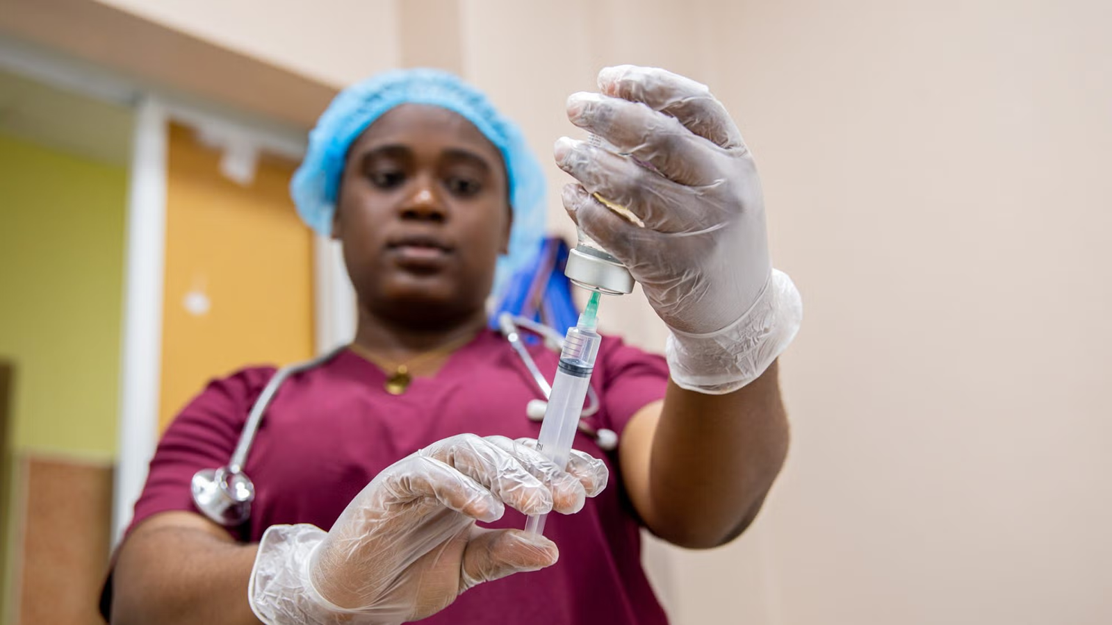 A medical worker draws a syringe full of medication from a vial