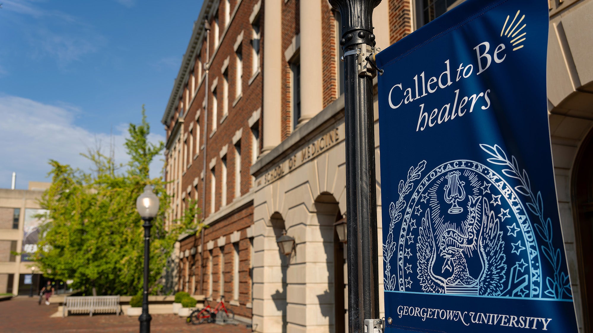 The exterior of the Med-Dent Building with a banner in the foreground reading Called to Be Healers Georgetown University