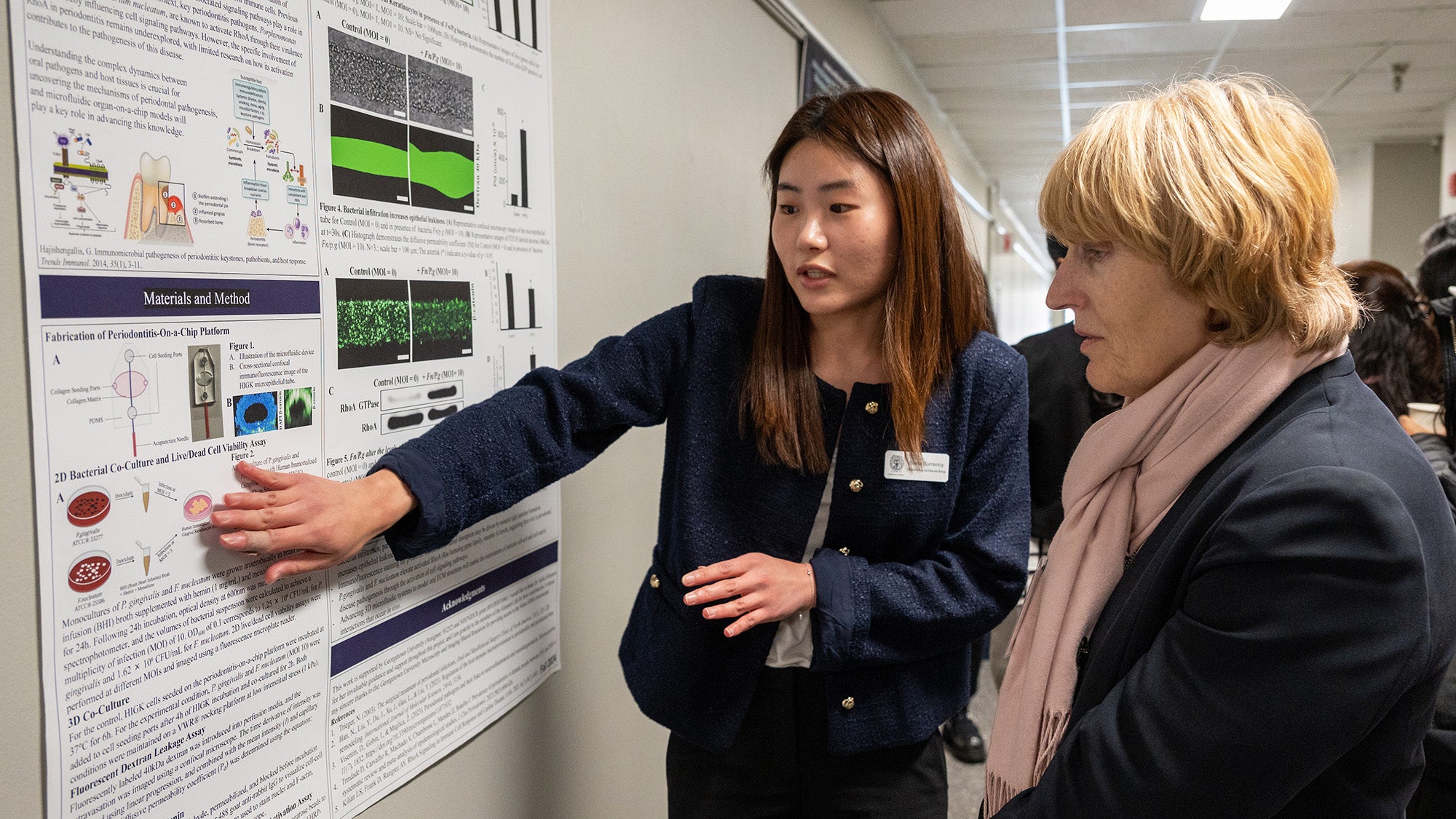 A graduate student presents her poster to a faculty member