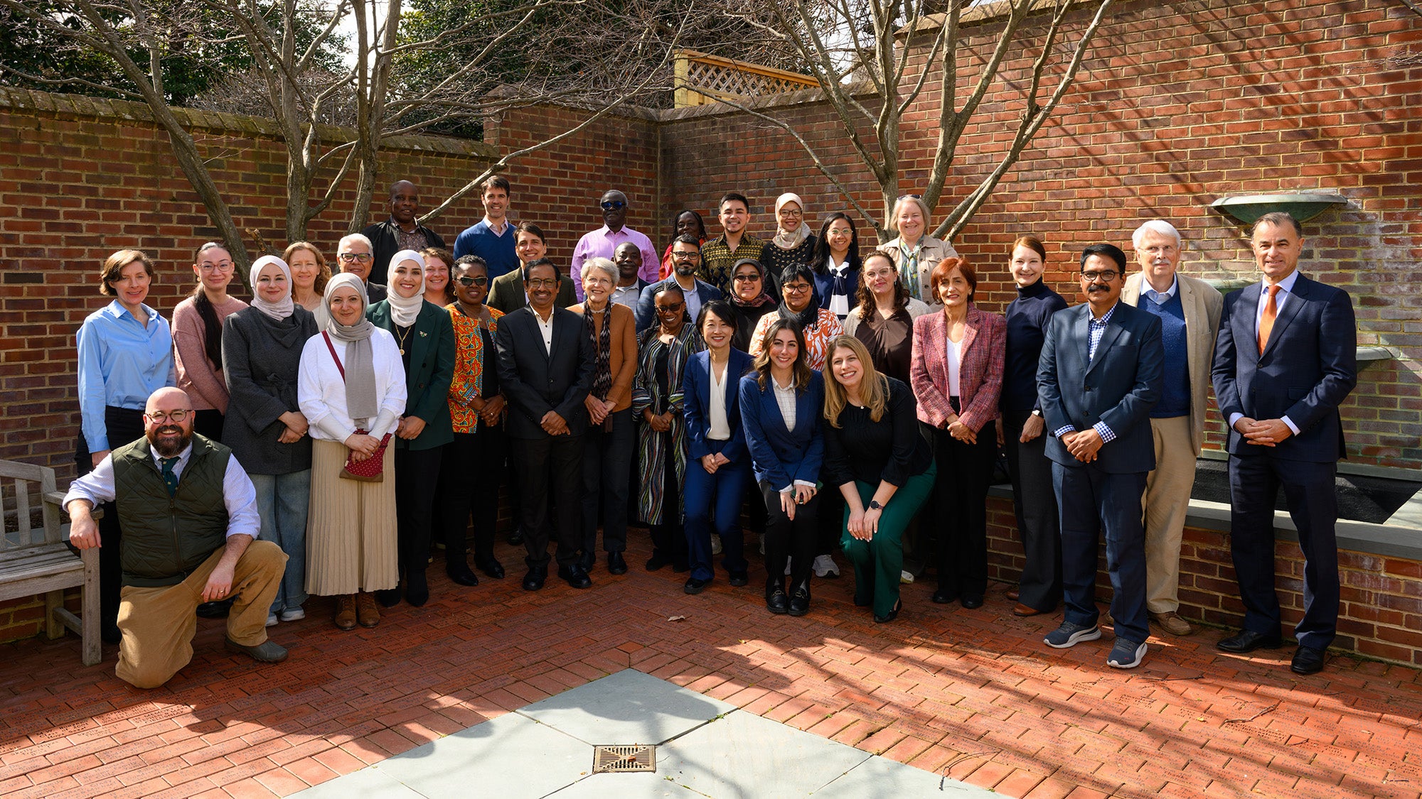 All participants in the Global Preceptors meeting stand together outdoors on campus