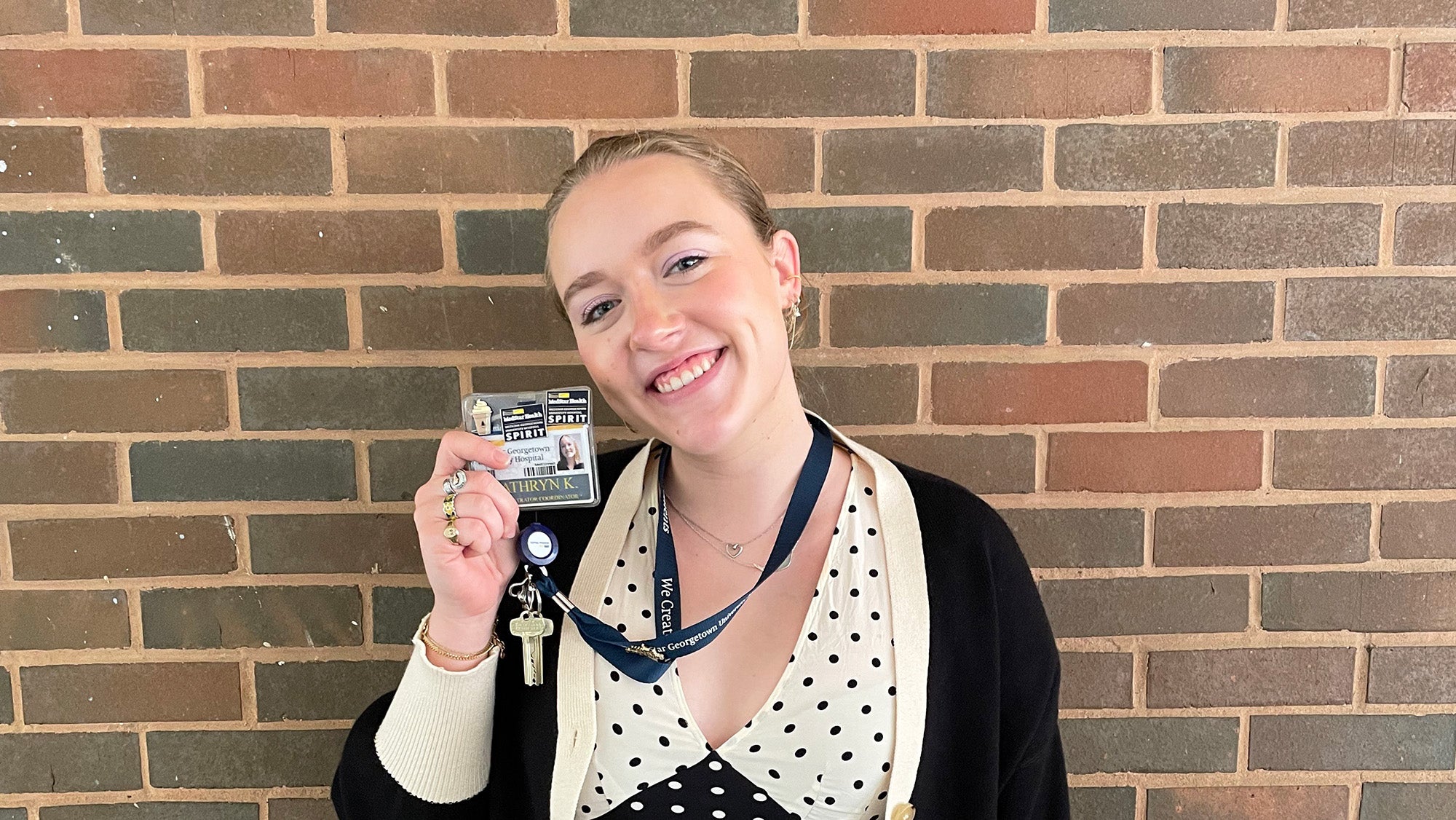 Katie Kalhorn holds up her name badge on a lanyard around her neck with pride