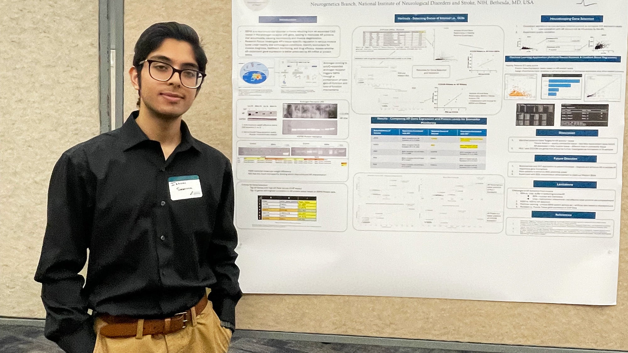Ishaan stands before his research poster at a conference