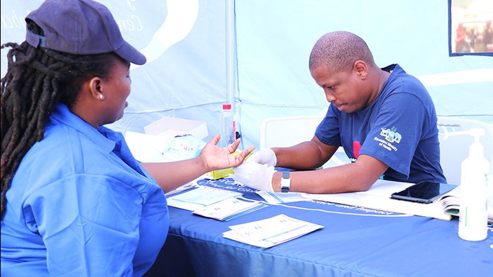 A worker gets her blood drawn by a worker at a table