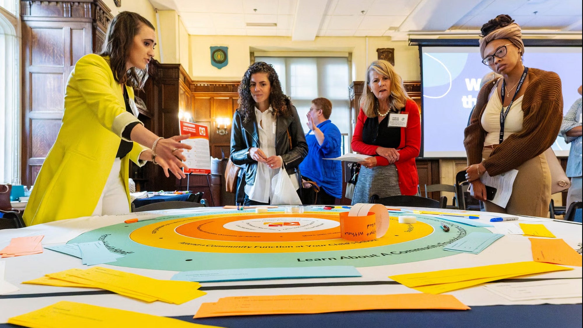A researcher with the Thrive Center explains her research to several individuals