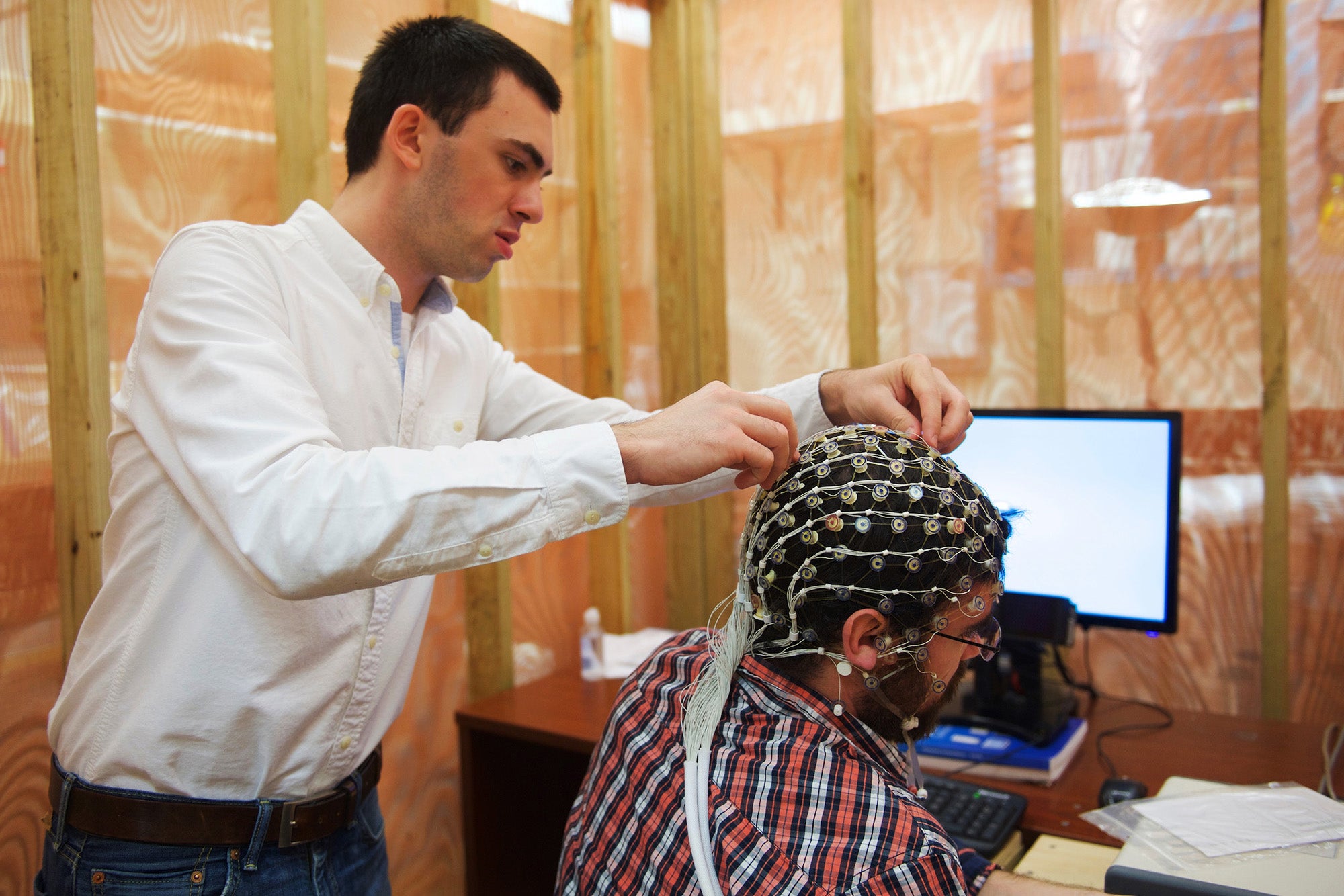 A student fastens a network of monitoring wires to a person's scalp