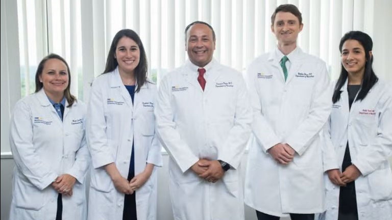 Fernando Pagan, MD, stands with four students in medical white coats