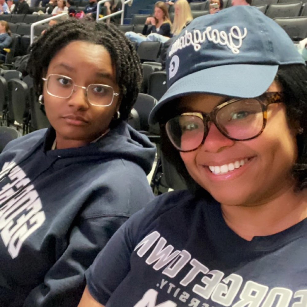 Aleria Butler and her daughter sit in seats at a sporting event