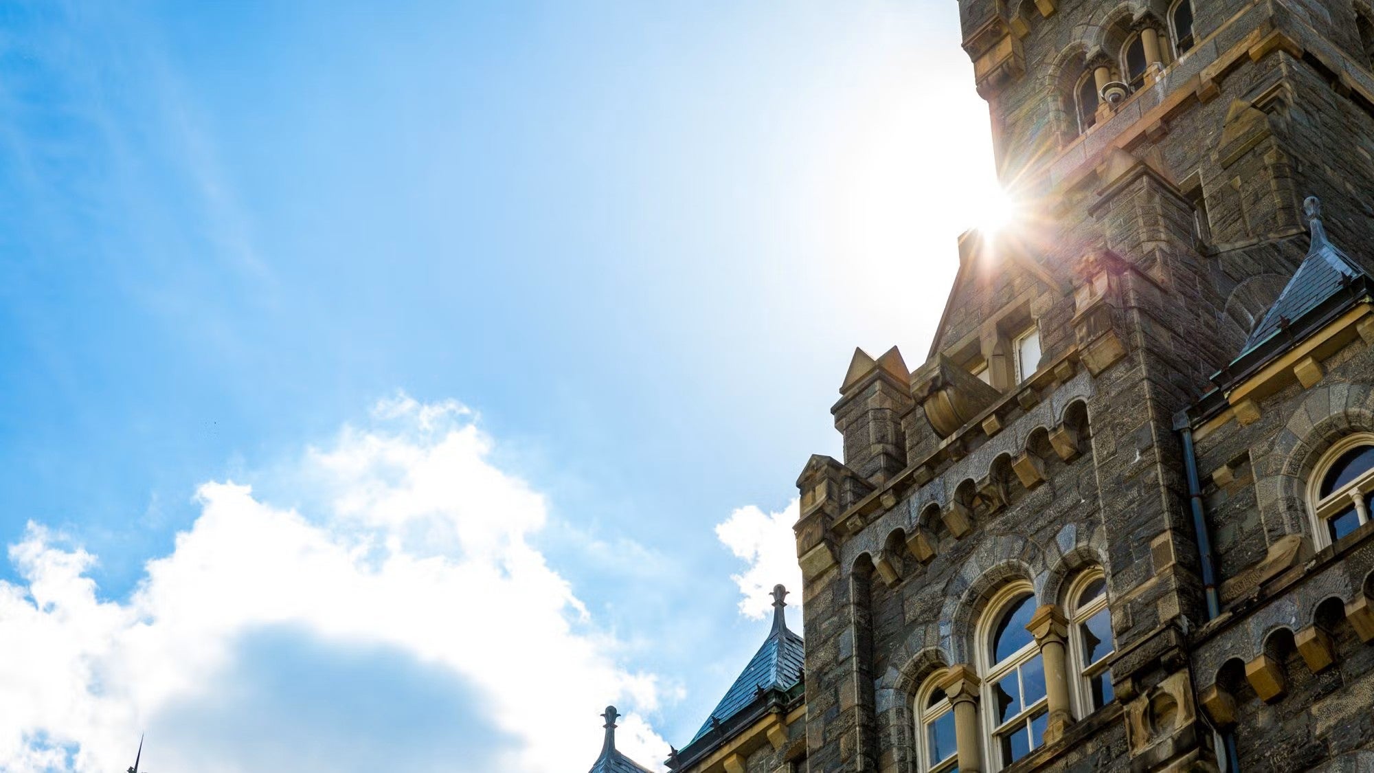 The sun shines around a roof detail of Healy Hall
