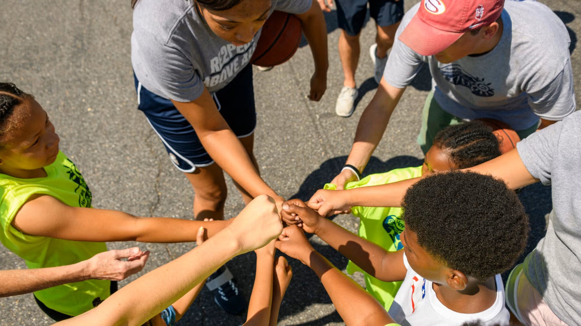 Participants in the HOYA Clinic Summer Sports Camp put fists together in a show of spirit