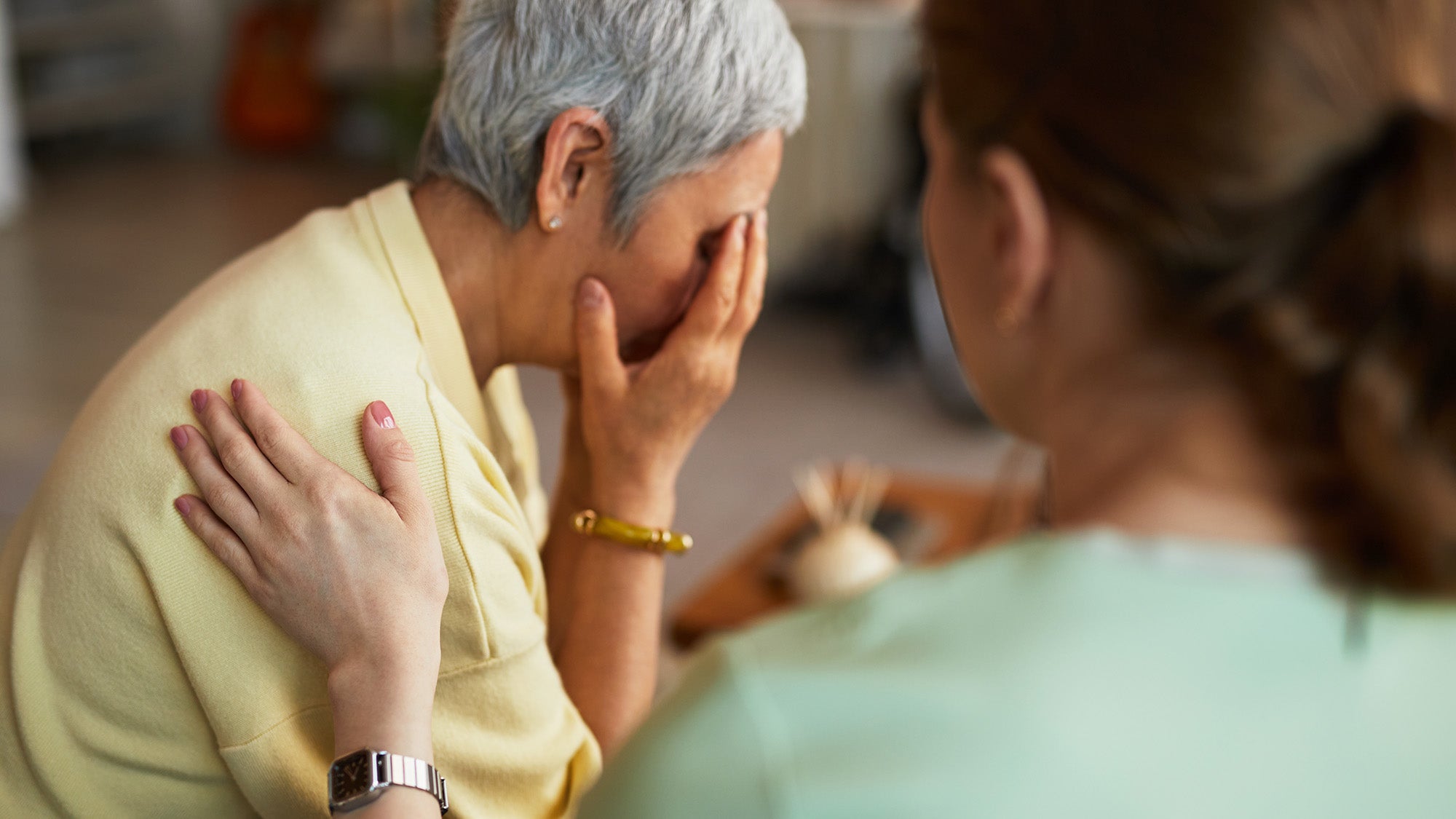 A caregiver comforts an older woman