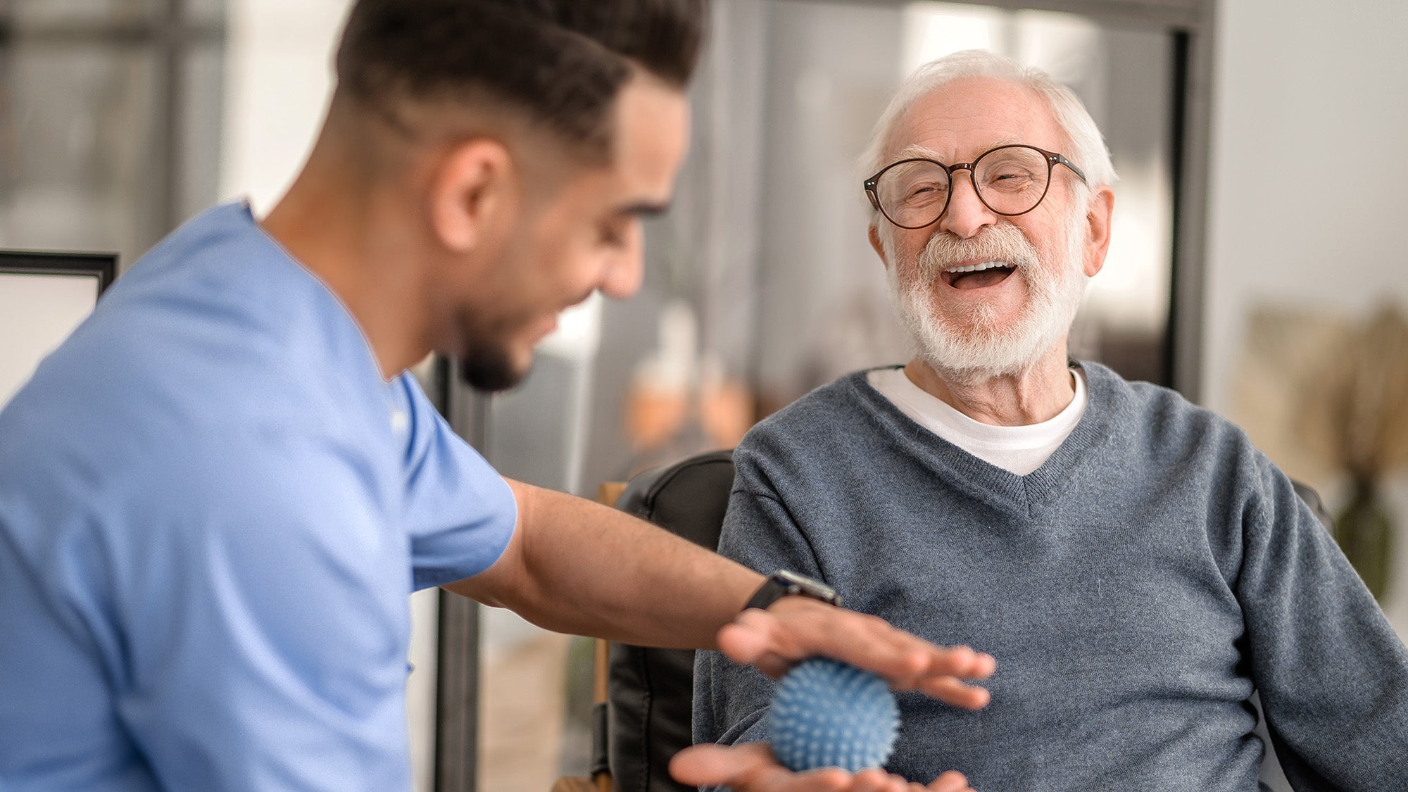 A physical therapist works with an older male patient