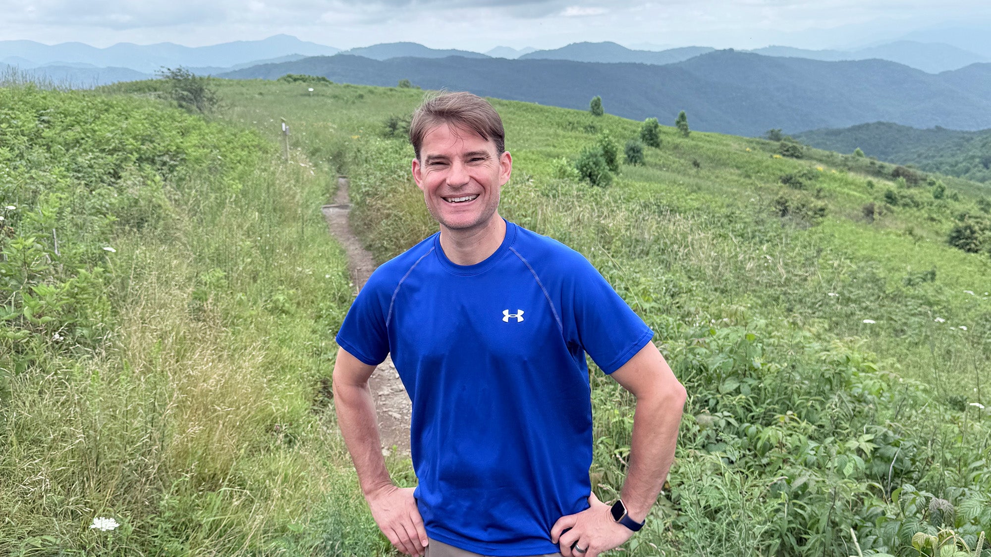 Scott Dorris stands in a field with hills stretching out behind him