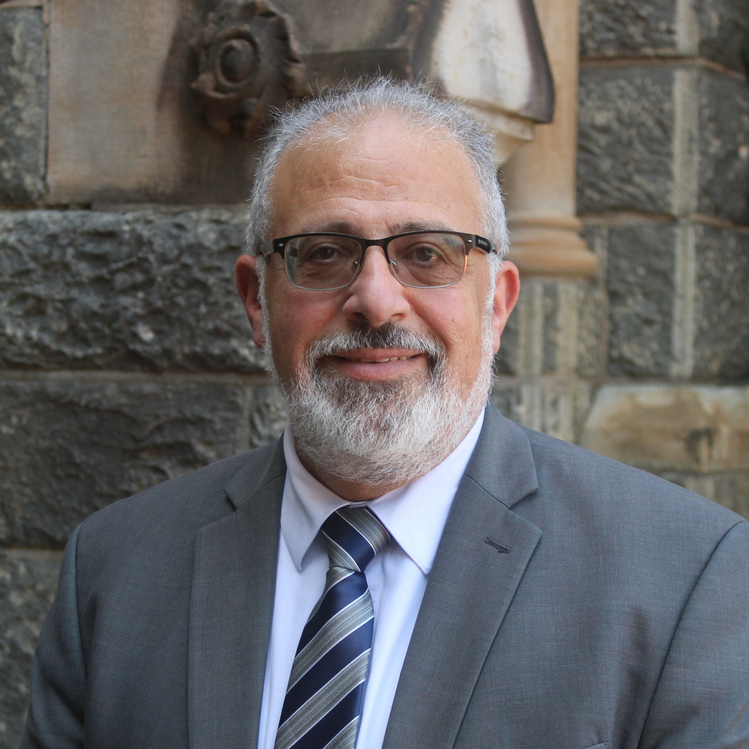 a man wearing glasses with grey hair and beard. 