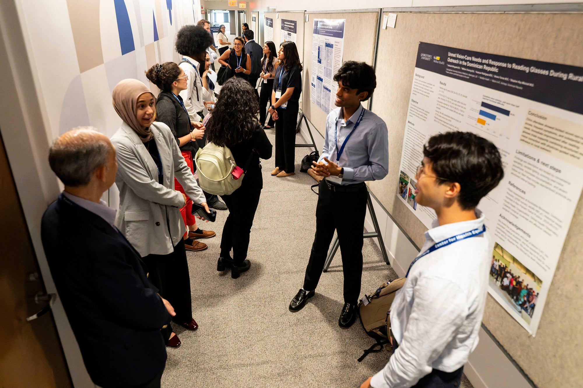 Two students speak to conference attendees in a hallway